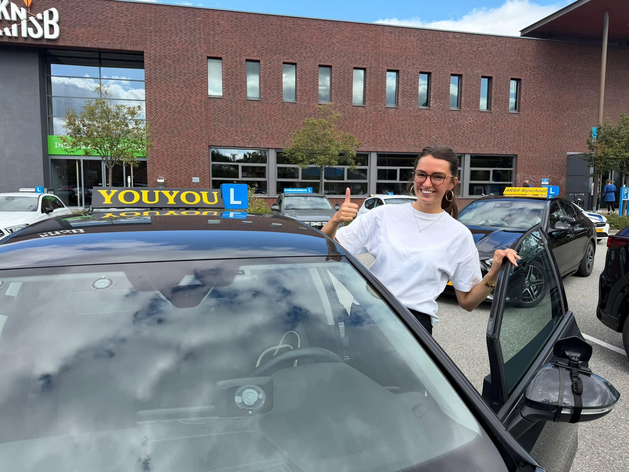 Geslaagde leerling Lisanne naast de lesauto